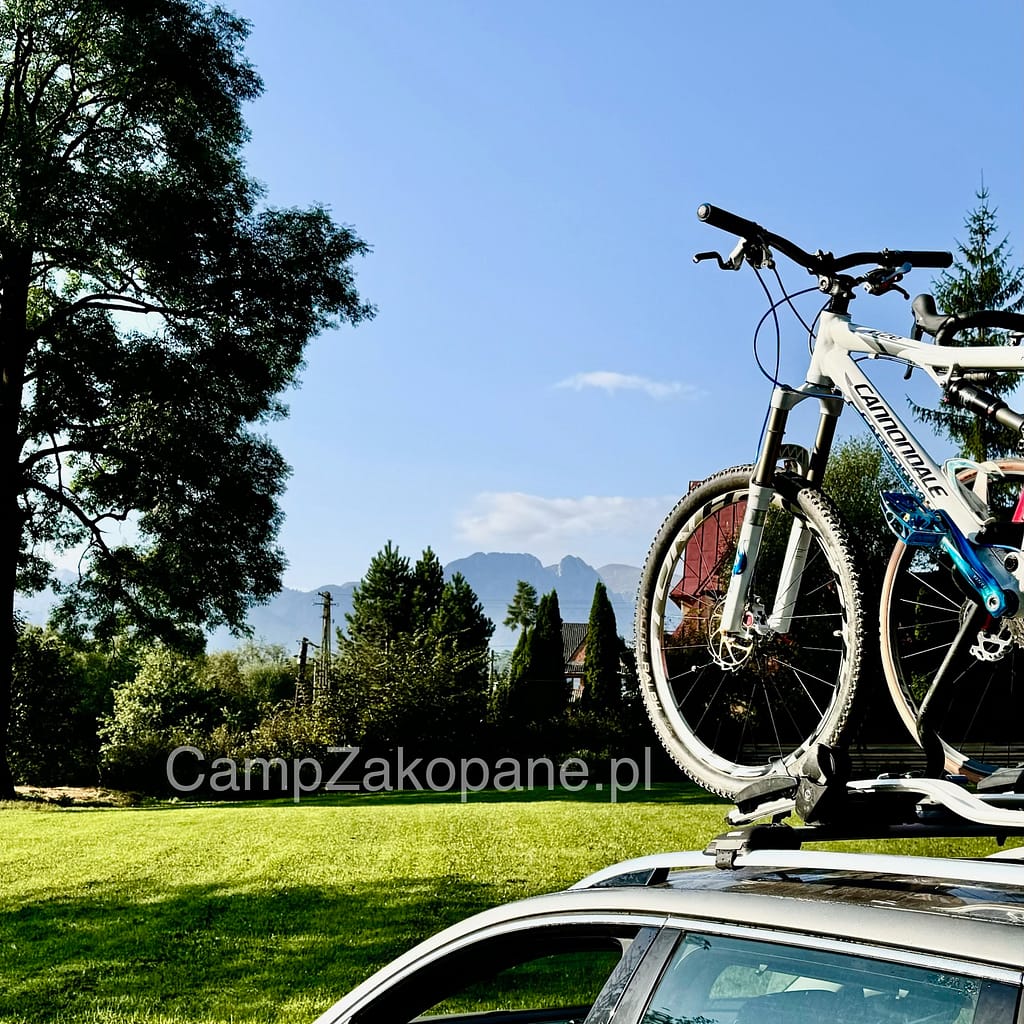 Rowery na tle Giewontu przygotowane na wycieczki po Tatrach na trawiastym terenie Camping Harenda w Zakopanem.