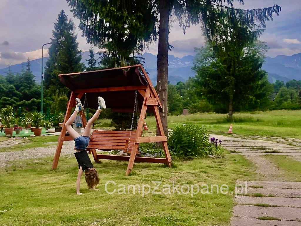 Dziecko ma dużo miejsca do zabawy przy huśtawce z widokiem na Tatry na Kemping Harenda w Zakopanem.