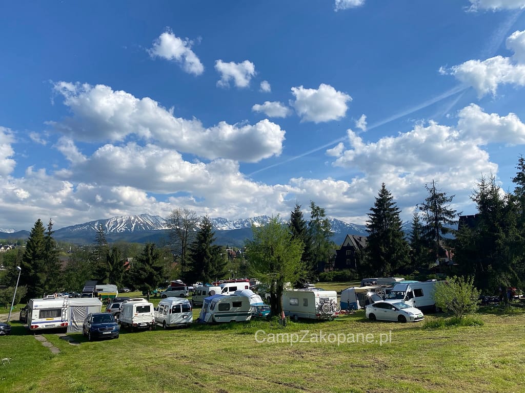 Stanowiska dla kamperów z widokiem na ośnieżone Tatry na Camping Harenda w Zakopanem w słoneczny dzień