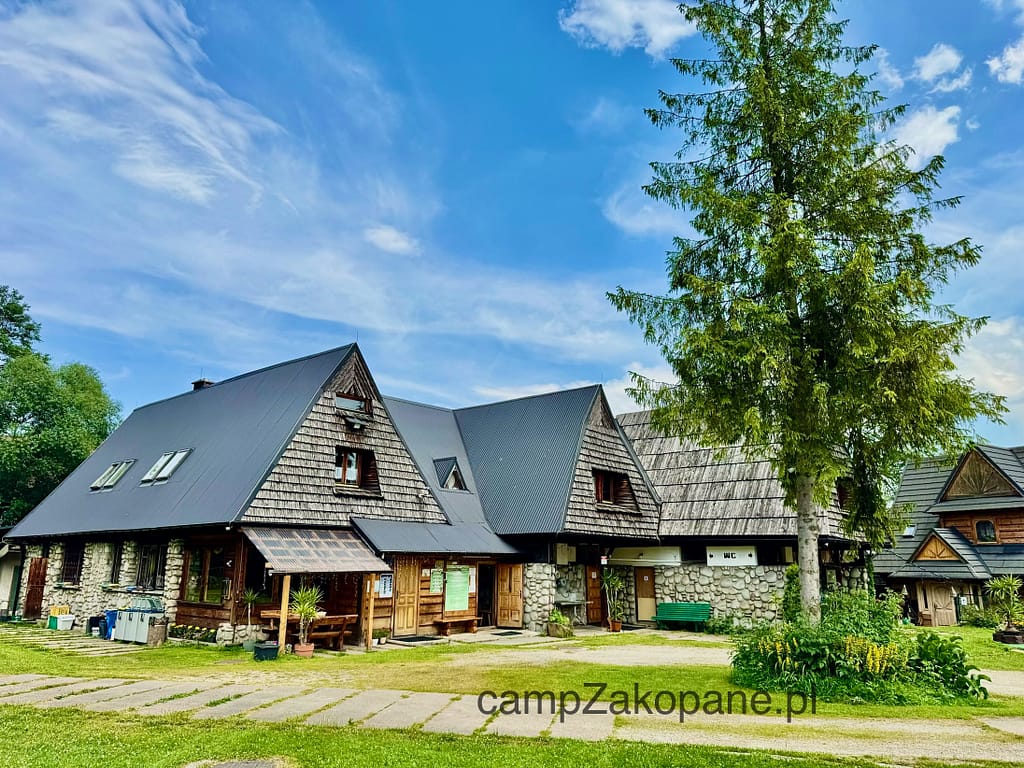 Noclegi Zakopane – Camp Harenda, główny drewniany budynek z recepcją i pokojami gościnnymi w stylu podhalańskim.