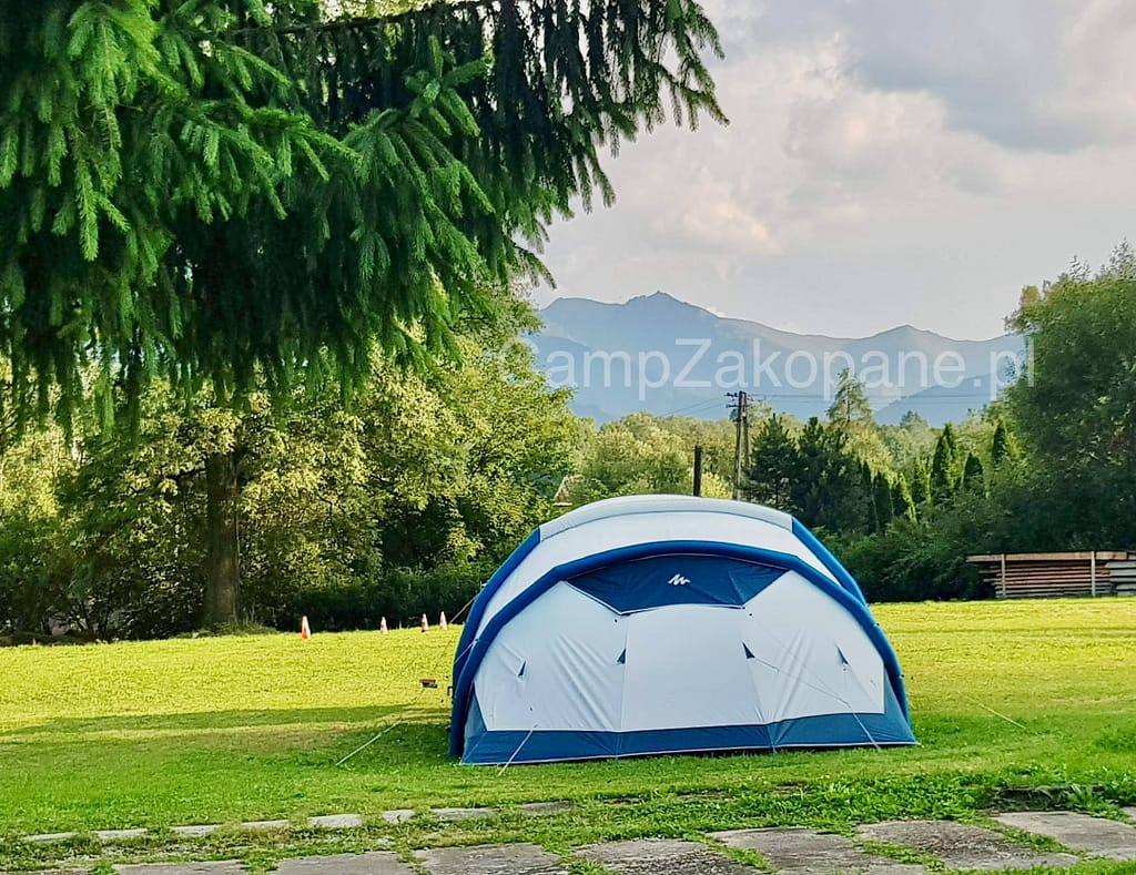 Namiot na zielonym polu namiotowym z widokiem na Tatry na Camping Harenda w Zakopanem.